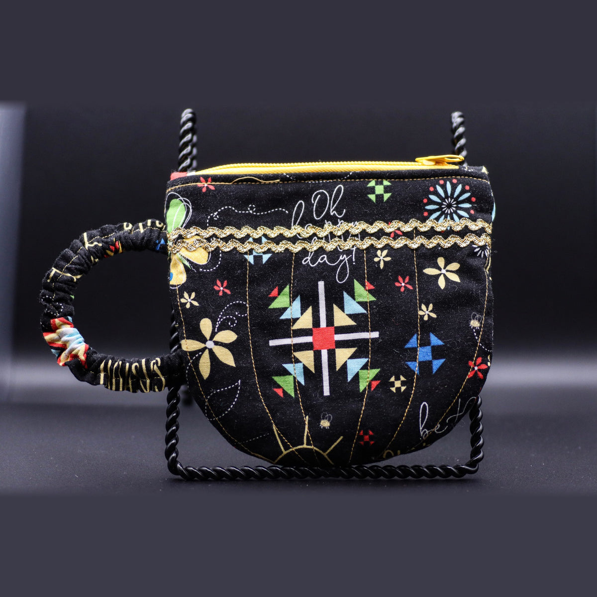 Teacup-shaped quilted bag in black with a floral print, front view
