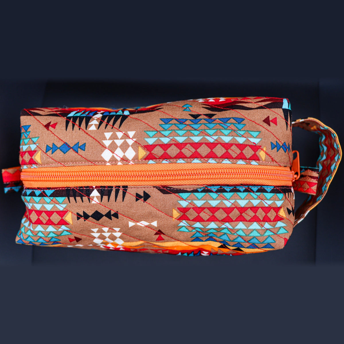Tan geometric boxy bag from above, showing the orange zipper
